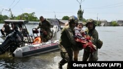 Украінскія вайскоўцы эвакуююць мясцовых жыхароў з затопленай зоны ў Херсоне пасьля прарыву Кахоўскай ГЭС, 8 чэрвеня 2023, фота AFP