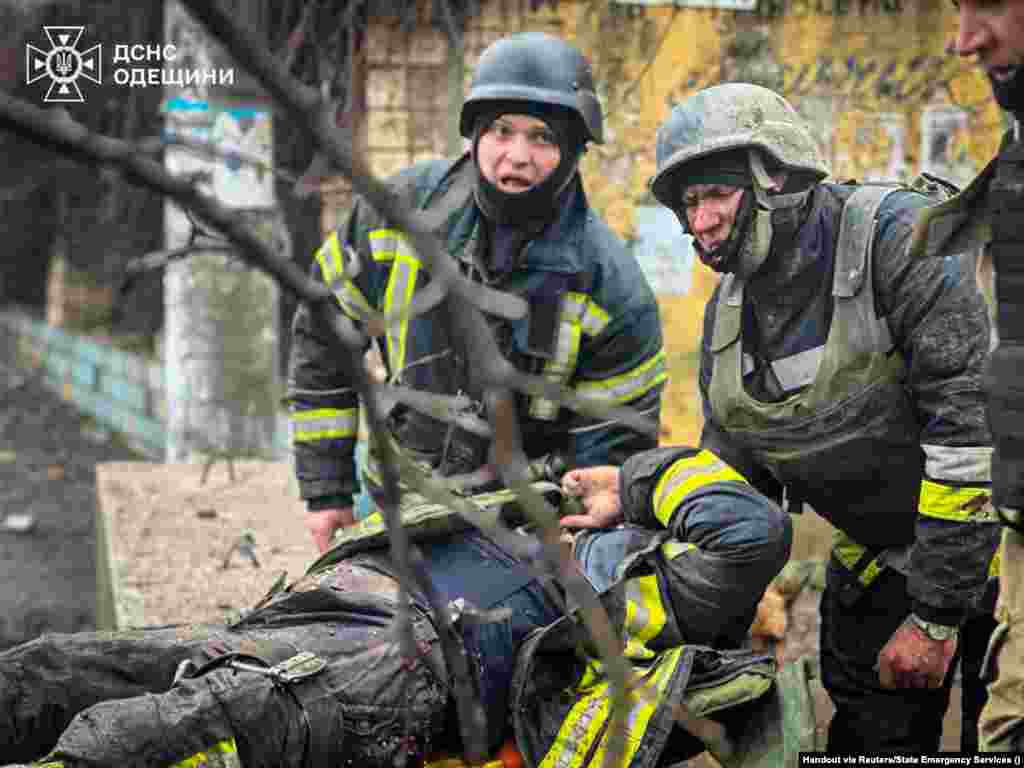 Ратавальнікі выносяць параненага калегу з месца ракетнага абстрэлу ў Адэсе 15 сакавіка 2024 года. Паводле афіцыйных зьвестак, сярод прынамсі двух дзясяткаў чалавек, якія загінулі ў выніку расейскага ракетнага ўдару ўдзень 15 сакавіка, былі мірныя жыхары, фэльчар і ратавальнік Дзяржслужбы па надзвычайных сытуацыях.