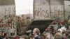 West Berliners crowd in front of the Berlin Wall early 11 November 1989 as they watch East German border guards demolishing a section of the wall in order to open a new crossing point between East and West Berlin