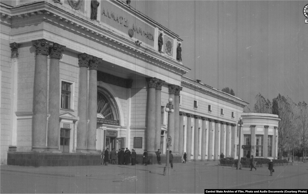 Здание железнодорожного вокзала в городе Алма-Ате. 1950 год (слева).&nbsp;В&nbsp; Верном &mdash; так назывался город до 1921 года &mdash; в этом районе располагалось кладбище. К моменту строительства вокзала погост был снесен селевым потоком. Здание строилось в 1936&ndash;1939 годах архитекторами Галкиным и Кудрявцевым. Пережило реконструкцию в 1977 году и капитальный ремонт в 2012-м. Выходящая к вокзалу улица четыре раза меняла свое наименование: названная Старокладбищенской во времена Верного, в 1933 году она превратилась в проспект Сталина, в 1961 году стала Коммунистическим проспектом, а сейчас называется Абылай-хана. 