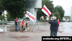 Мінак фатаграфуе бел-чырвона-белыя сьцягі ў цэнтры Баранавічаў